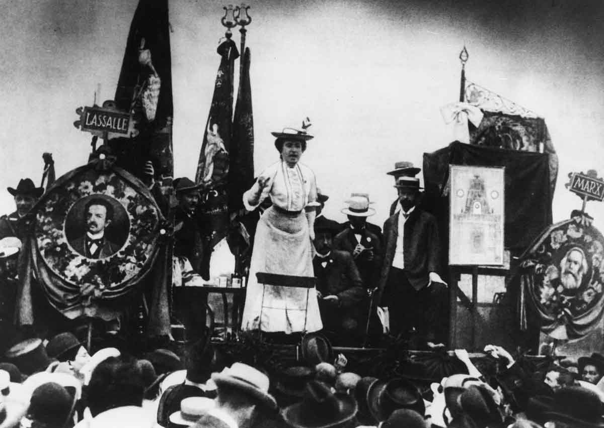 Rosa Luxemburg addresses a Stuttgart crowd in 1907. Here she is flanked by portraits of Karl Marx (right) and Ferdinand Lassalle (left), the founders of the German Socialist movement.