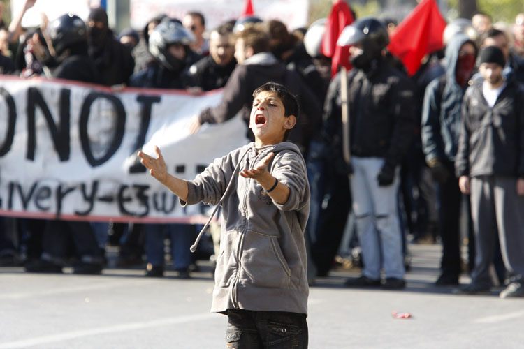 A boy shouts at riot police during a demonstration in front of the Greek parliament building in Athens